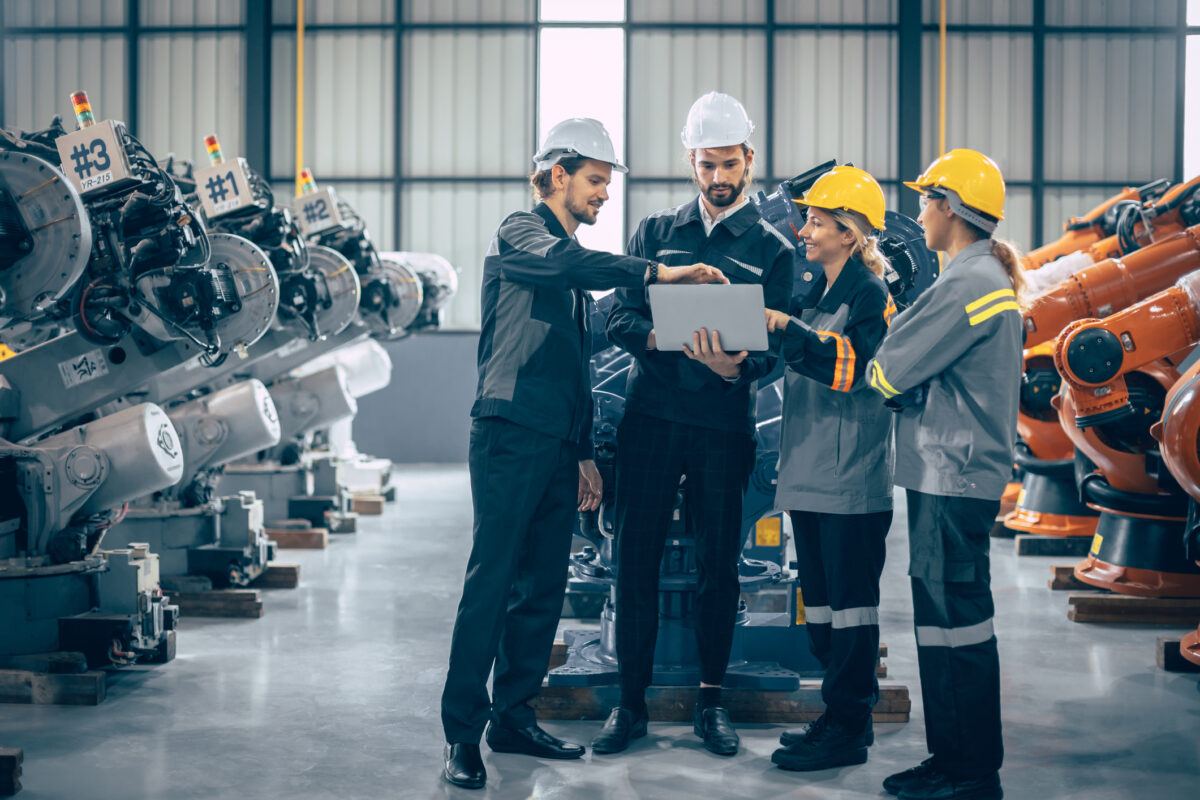Group of engineer team stand talking together. Industry engineering teamwork people discussion. Robot arm design assembly plant meeting with laptop computer for exchange knowledge.